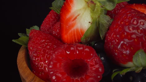 Köstliche-Rotierende-Waldbeeren-In-Einer-Holzschale,-Nasse-Helle-Früchte,-Erdbeeren,-Blaubeeren,-Himbeeren,-4K-Makroaufnahme