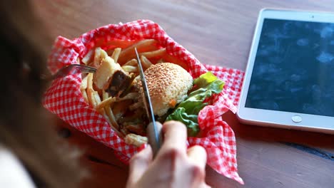 Woman-cutting-burger-with-fork-and-knife-in-a-restaurant