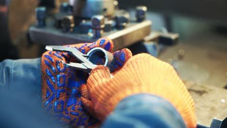 worker professionally measuring the shaped material on lathe