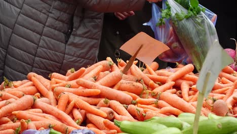 people buying carrots at a farmers market