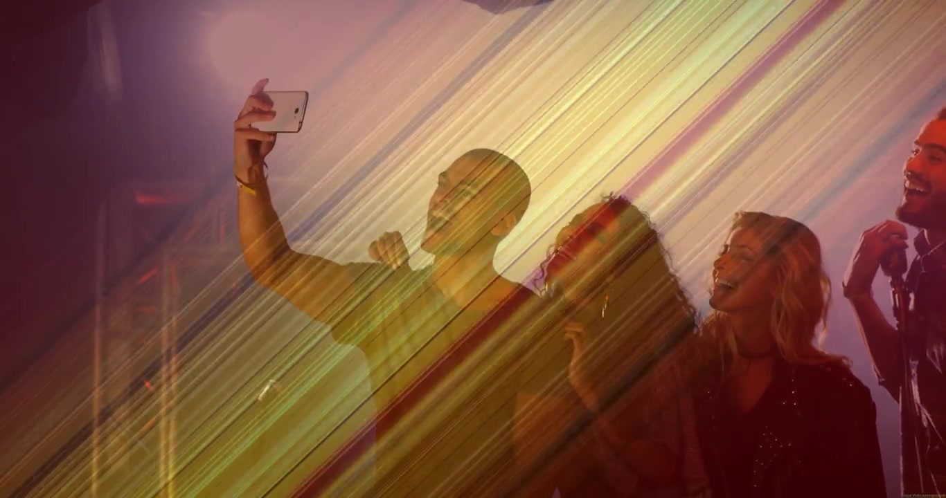 Uomo che alza il telefono bianco, scattandosi un selfie a un evento dal vivo, catturando il divertimento con strisce diagonali che si incrociano