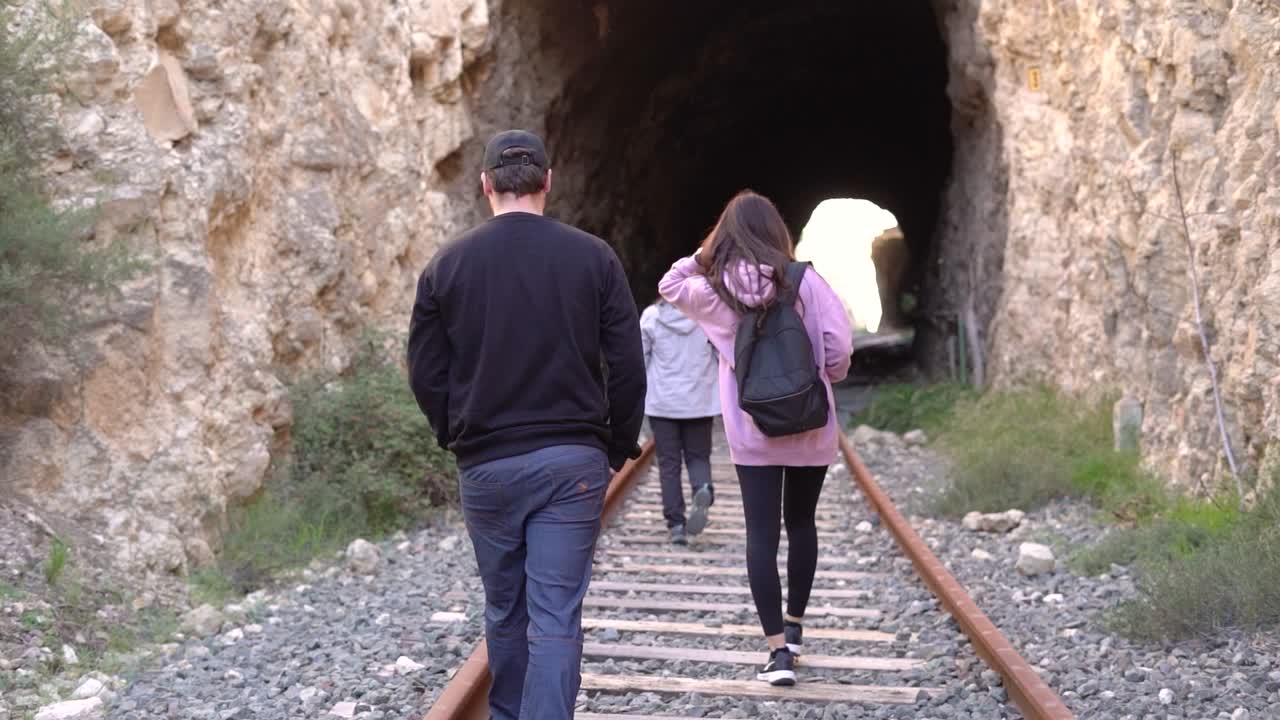 People walking on abandoned railway. Forgotten paths hiker group of backpacker friends. Hiking adventure in nature.
