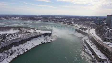 wide aerial pull-out of niagara falls and surroundings in winter