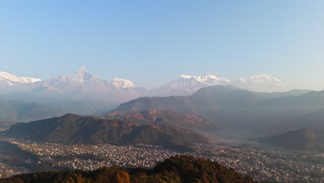 aerial: pokhara city and snowy annapurna mountain range, hazy morning in nepal