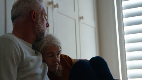 depressed senior woman suffering with poor mental health being comforted by husband  at home