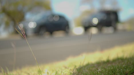 a blue mitsubishi lancer pulls off a busy highway, slightly out of focus, sits idly, hinting at the routines and rhythms of daily life.