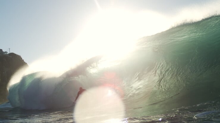 Onda che si infrange al rallentatore con texture illuminate dal sole e spruzzi