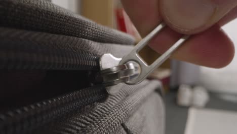 close up of person at home zipping up and unzipping suitcase on summer holiday