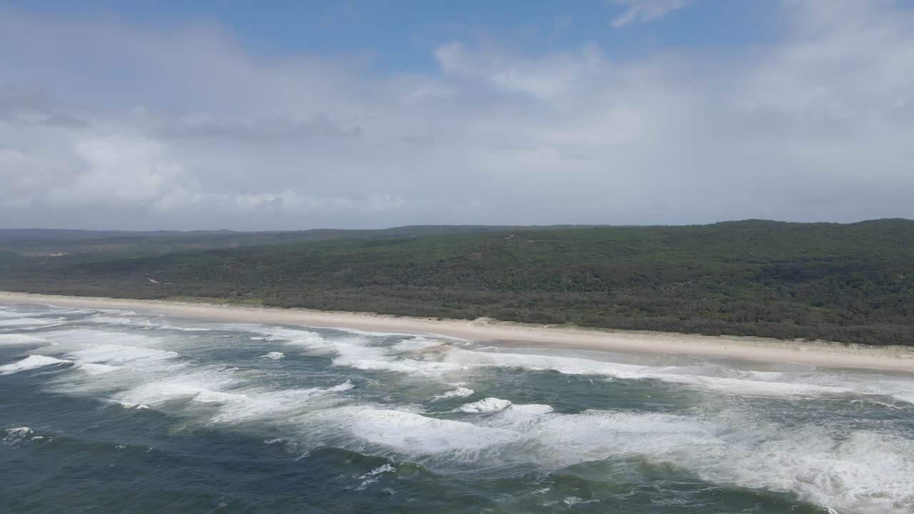 olas espumosas en la playa principal con un vasto bosque en el punto de observación, qld australia