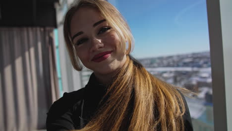 smiling red-haired young adult lady takes selfie. big-eyed pretty woman steps back before the camera. close up.