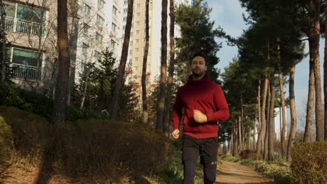 caucasian runner jogging in an urban city park - low angle front view