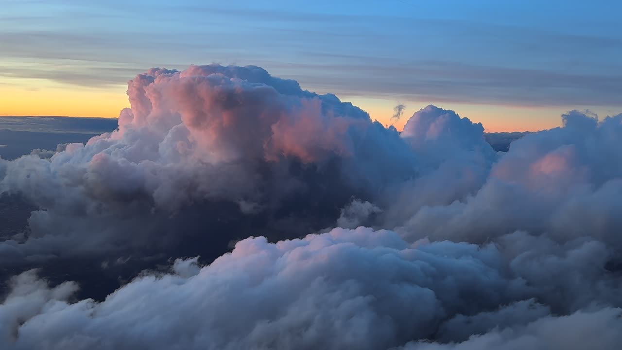 Twilight flight near some storm cloiuds bathed by purple sunset light at the golden minute. Aerilal view taken from an airplane cockpit. Handlehd camera shot