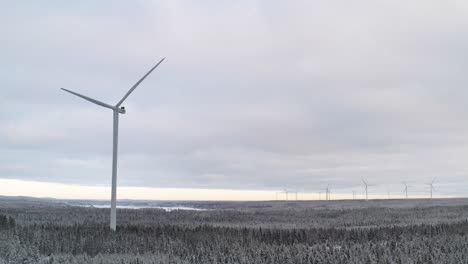 Turbina-Eólica-En-Un-Paisaje-Invernal-Lleno-De-Nieve,-Vista-Panorámica-De-Un-Parque-Eólico-Durante-Un-Día-Frío