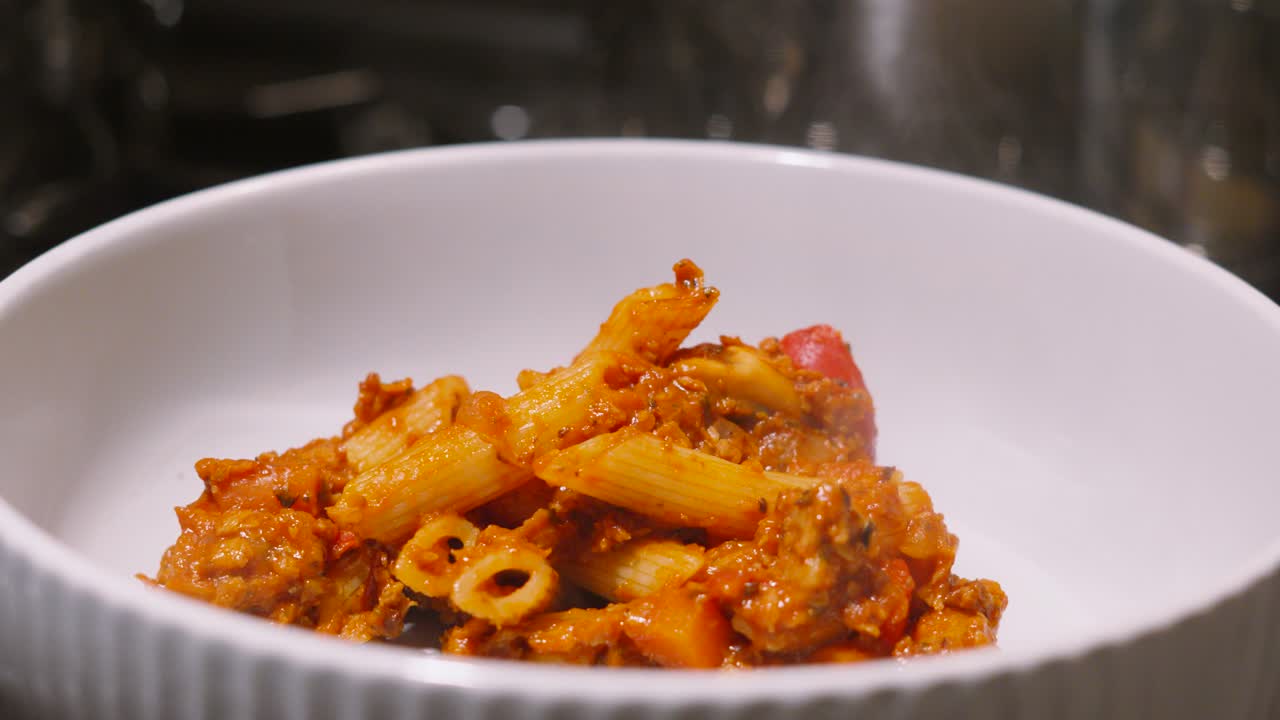 Penne Pasta Bake Being Plated in Bowl in Kitchen Environment. Easy Cooking Food Ready to Eat.