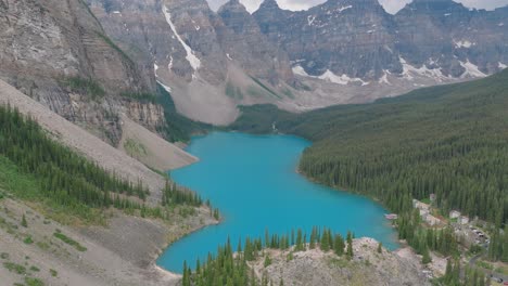 aerial orbit over emerald lake moraine surrounded by mountains and pine tree forest at banff national park, alberta, canada