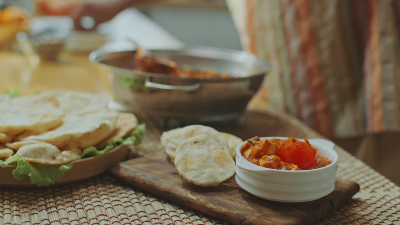 añadir cilantro fresco a un plato indio servido con pan plano en una tabla de madera