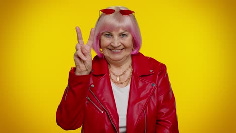 Mature-grandmother-showing-victory-sign,-hoping-for-success-and-win,-doing-peace-gesture,-smiling