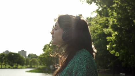 atractiva joven italiana con auriculares escuchando música en el parque con una mirada de puesta de sol alrededor de la sonrisa, bailando, disfrutando de la vida