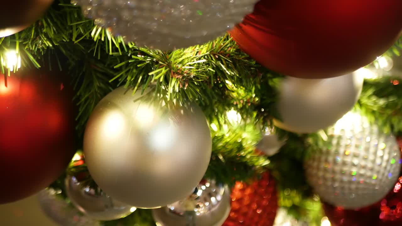 primer plano de un árbol de navidad al aire libre decorado festivamente con bolas rojas brillantes en un fondo de hadas brillantes borrosas. luces de guirnaldas desenfocadas, efecto bokeh. feliz navidad y feliz concepto de vacaciones.