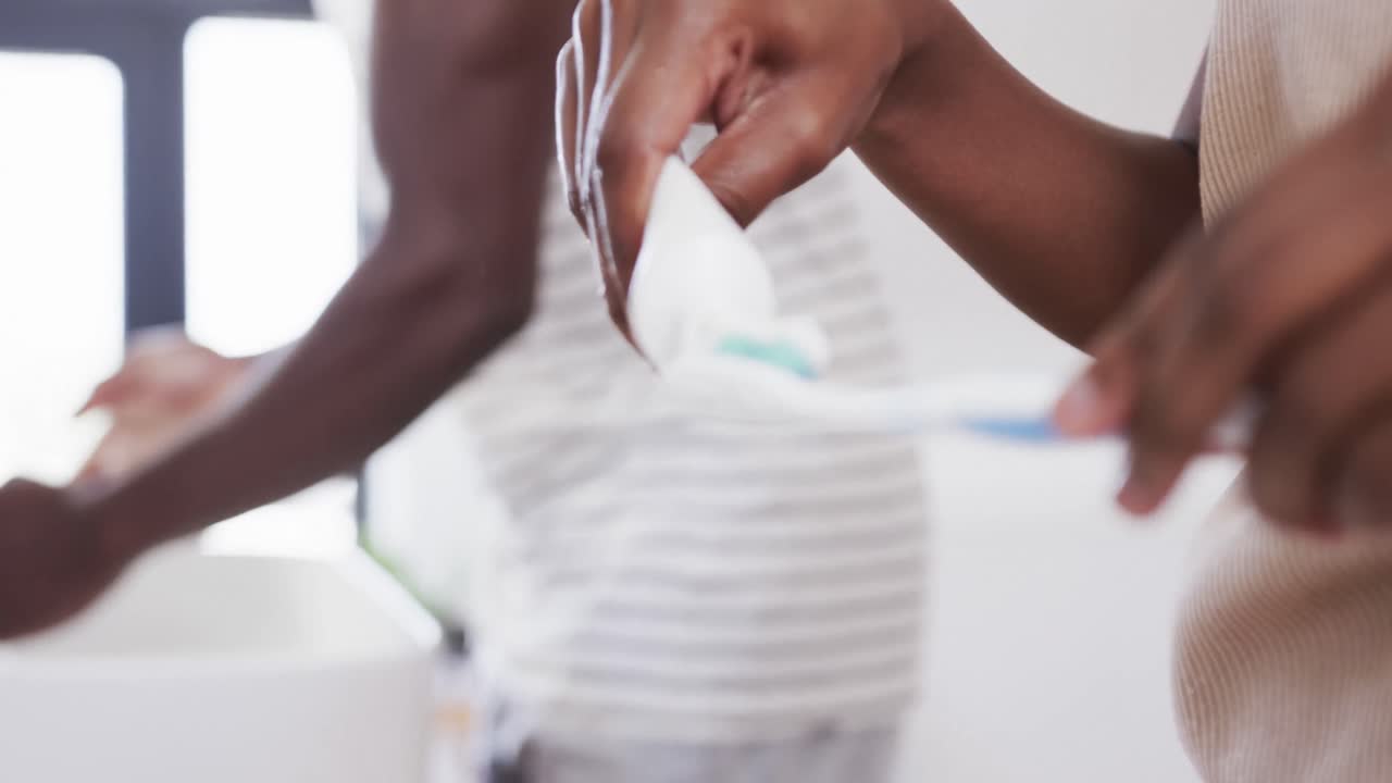 아프리카계 미국인 커플이 화장실에서 함께 치아를  ⁇ 는 중간 섹션, 복사 공간, 슬로우 모션