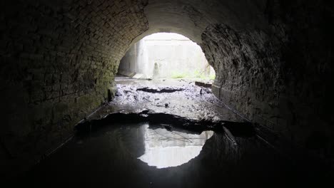 old brick abandoned semicircular drainage tunnel that goes outside.