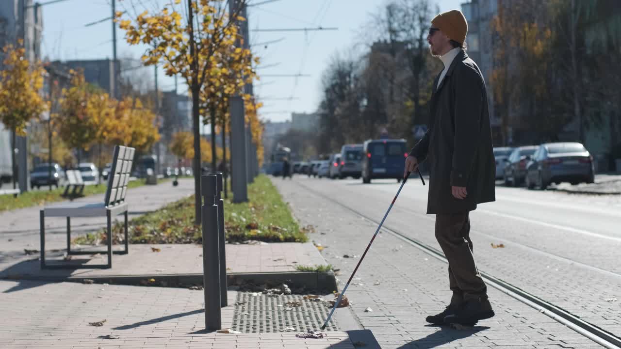 시각장애인 남자가 자신의 지이로 도로를 건너고 있는 모습이 도시에서 시각장애인을 위한 촉각적인 보행자 보행자 도로의 도움으로 보여진다.