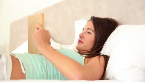 Morena-Acostada-En-La-Cama-Leyendo-Un-Libro