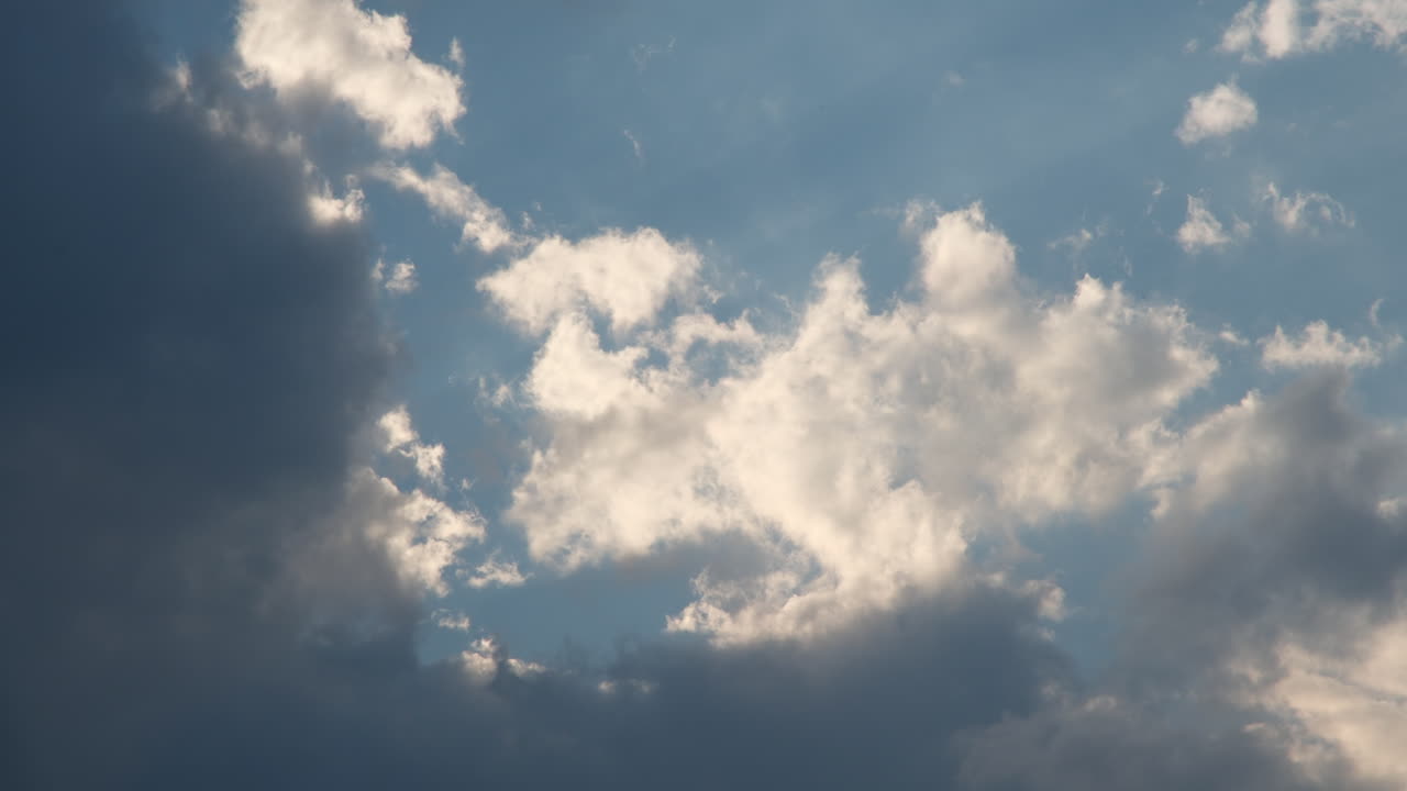 Moving summer clouds time lapse against blue sky and sun rays