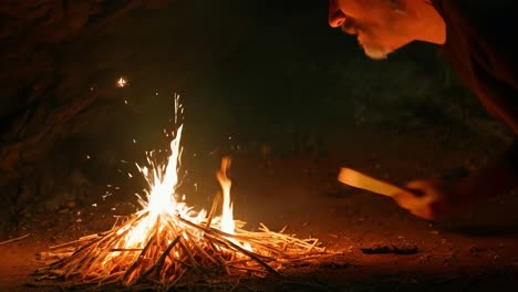 un hombre mira fijamente a un fuego en una cueva