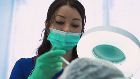 woman in mask does anti-aging injections to middle aged lady