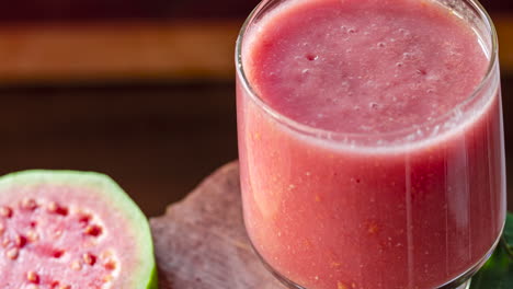 Glas-Roter-Guavensaft-Und-Geschnittene-Guavenscheibe-Auf-Hölzernem-Hintergrund