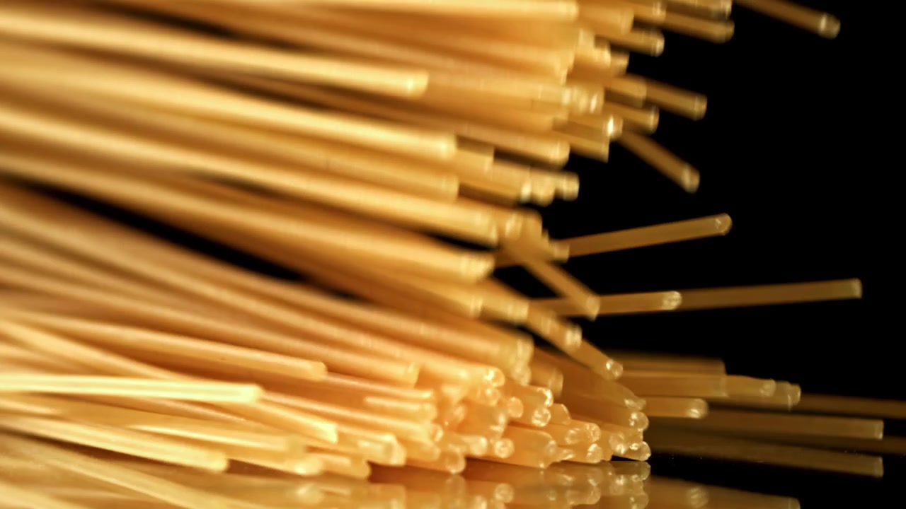 反射する表面にスローモーションで落下する乾燥スパゲッティパスタ