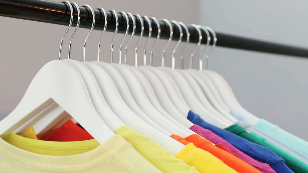 Various t-shirts arranged in a row on cloth rack 4k