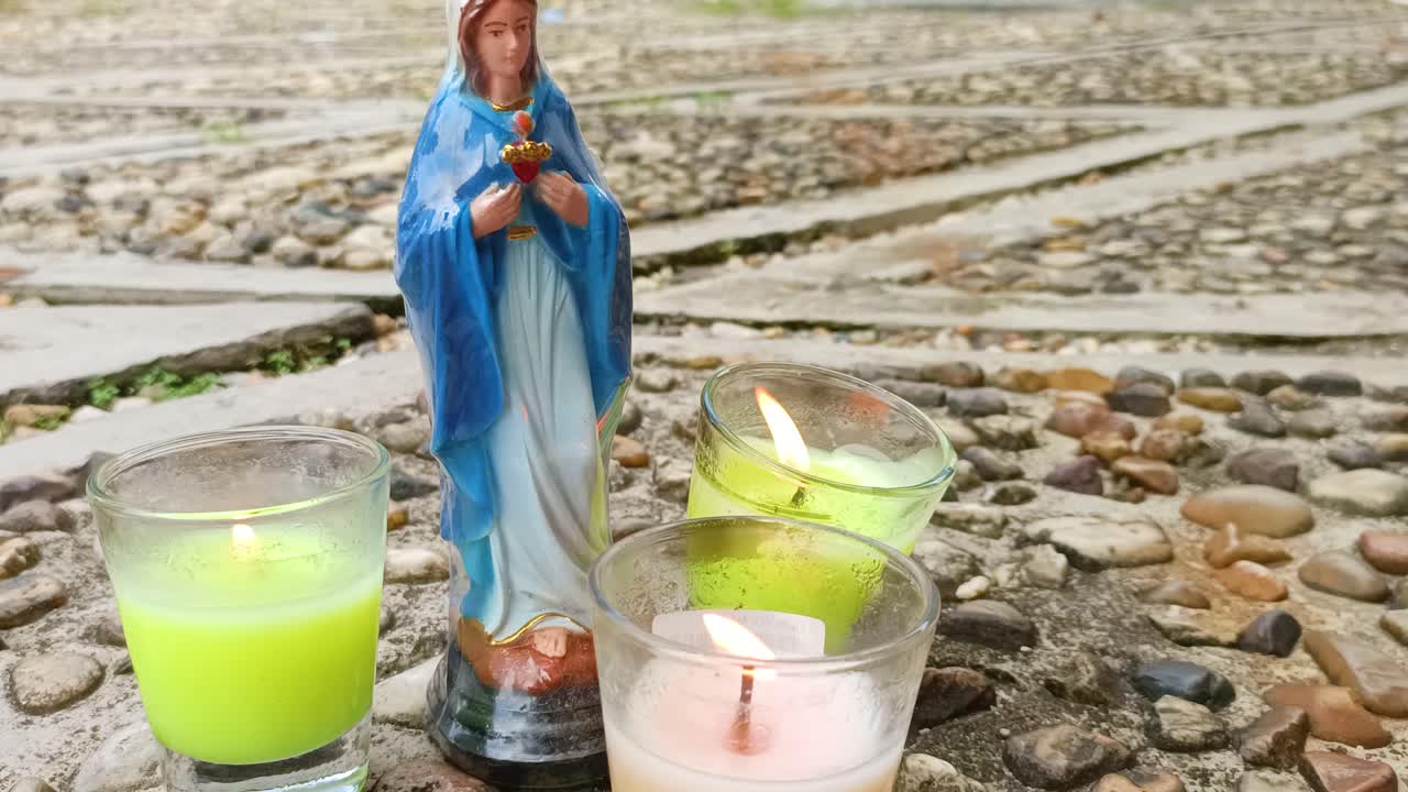 tres velas y una estatua de la virgen maría