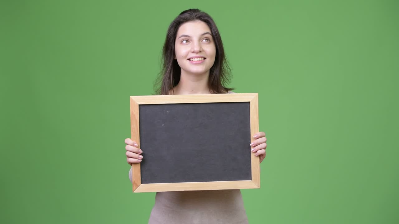 Young happy beautiful woman thinking while holding blackboard