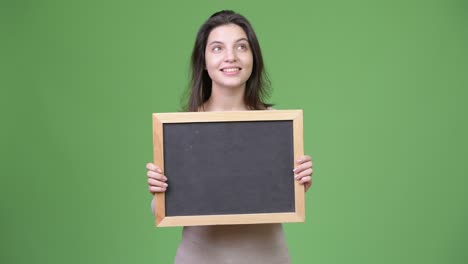 young happy beautiful woman thinking while holding blackboard