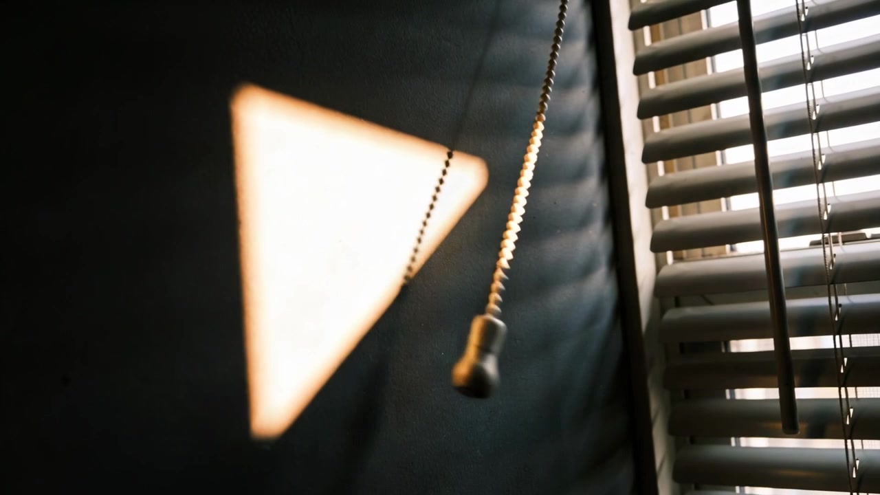 Projecting sun triangle on wall at home, sun shifting through blinds and beaded pull chain swinging