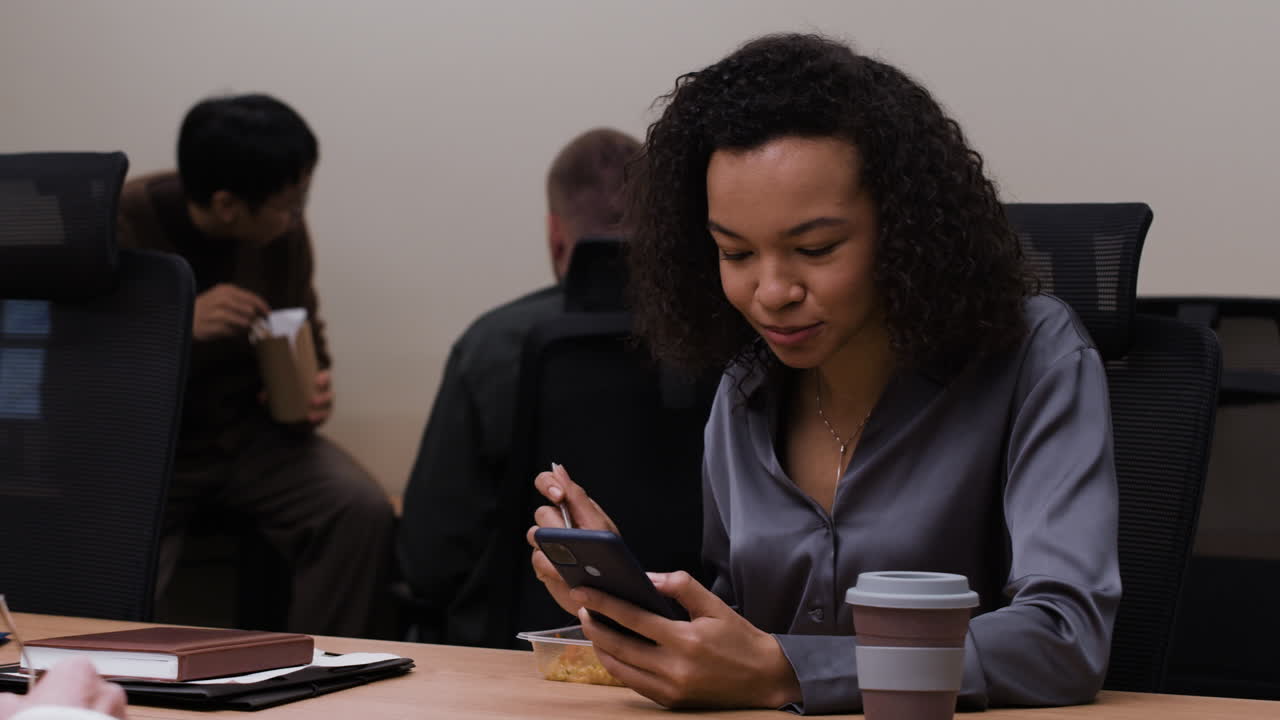 Businesswoman Eating Lunch and Using Phone in Office