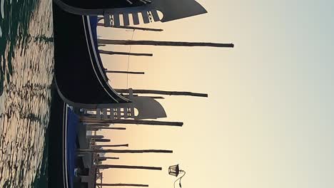 low angle water surface view of row of docked gondolas at sunset, venice in italy