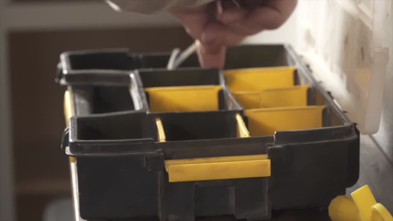 Close-up of a Man's Hands Opening a Plastic Toolbox Filled with Tools