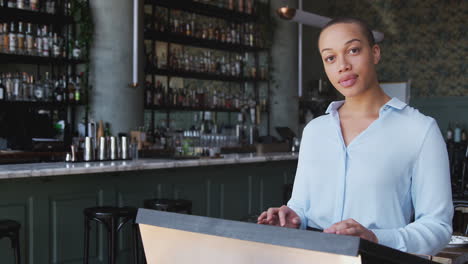 Portrait-Of-Female-Owner-Of-Restaurant-Bar-Standing-By-Counter-Checking-Reservations-Before-Service