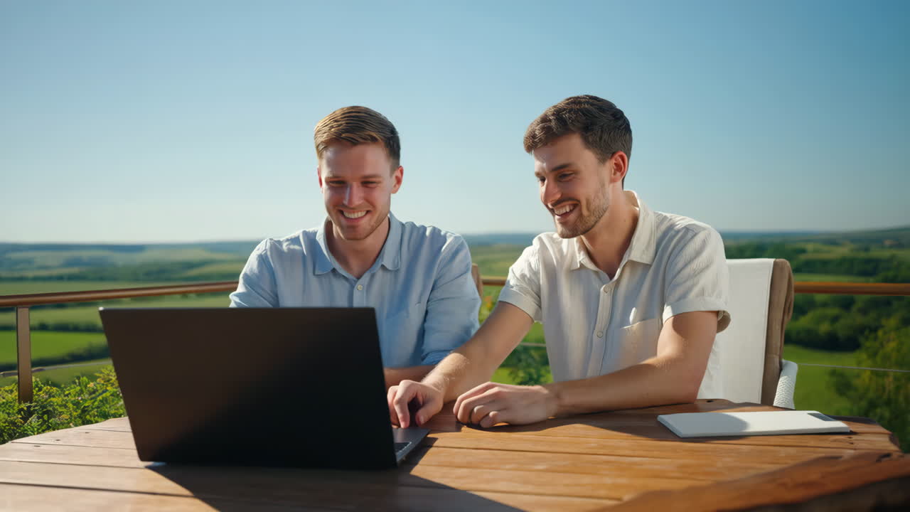 Two men working on a laptop outdoors