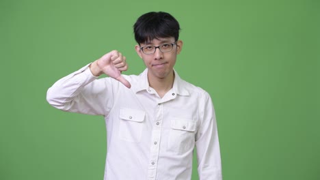 young asian businessman nodding head no and giving thumbs down