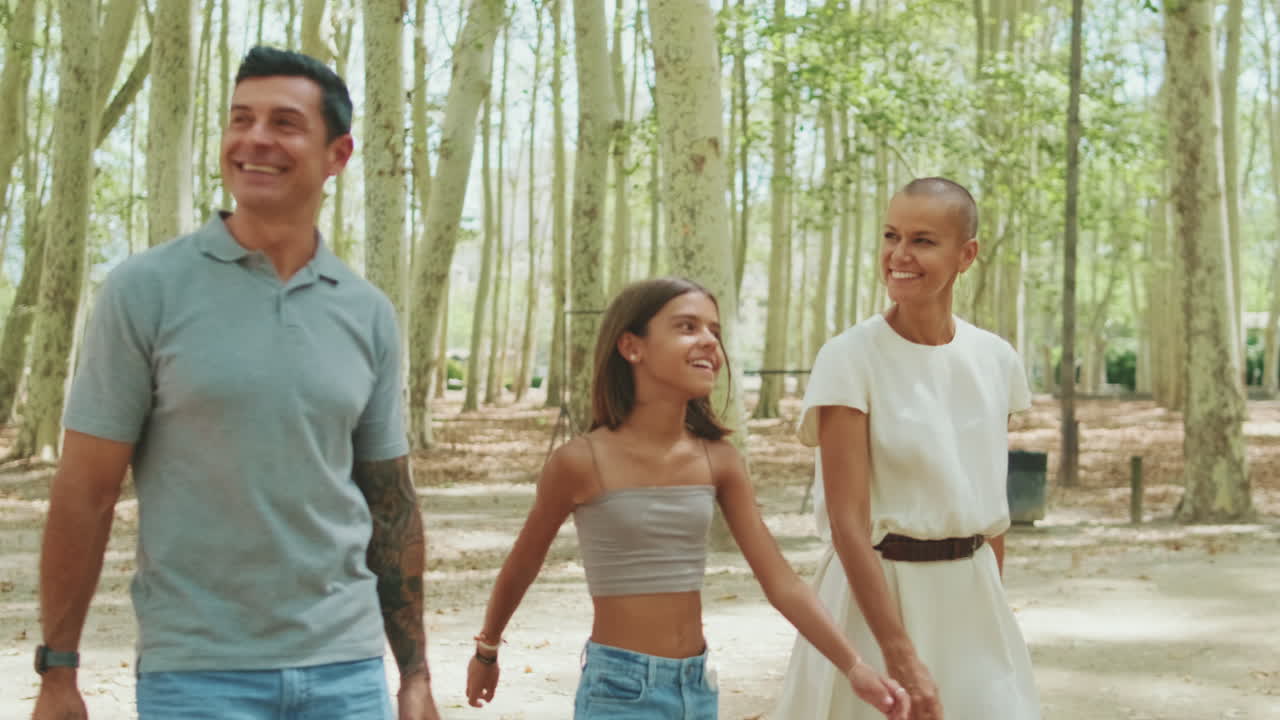 Glückliche Familie, die zusammen in einem grünen Park spaziert