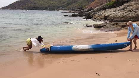 couple putting a kayak on the beach