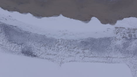 Aerial shot of snow, sandy beach and the waves at famous surfing spot Ervik