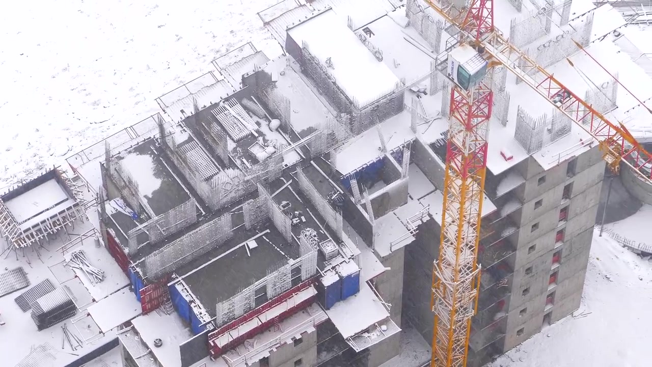 Aerial View of Construction Site During Winter Snowfall