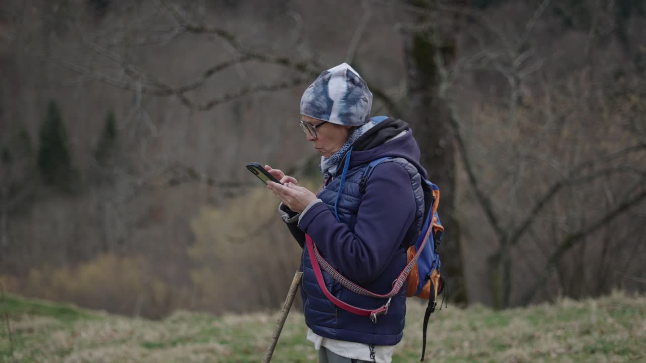 Woman Hiking and Using a Smartphone in a Forest
