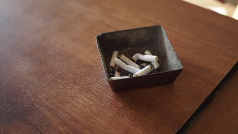 cigarette butts in an ashtray on a wooden table