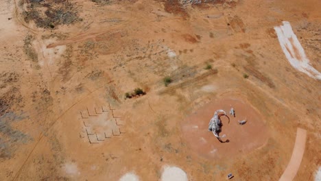 Drohne-Fliegt-über-Einen-Seltsamen-Park-Mit-Einer-Dinosaurierstatue-Im-Australischen-Outback